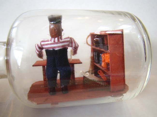 A wonderful small ship-in-a bottle depicting a sailor making a ship-in-a bottle — image 4